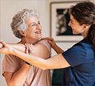 Nurse assisting and older women to stretch her arm