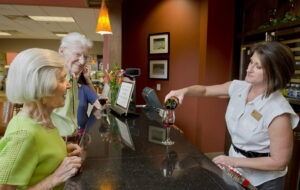 Bartender pouring a glass of wine for man and woman at the counter