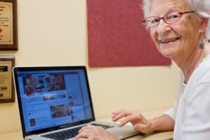 Woman looking over her shoulder and smiling at camera while using her laptop