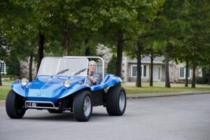 Man driving small blue convertible vehicle