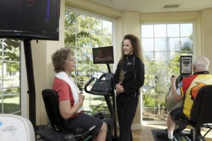 Fitness instructor talking to woman on stationary bike in fitness room