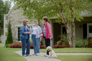 Three women standing and chatting outside of building entrance with a dog on a leash