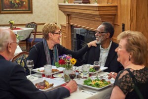 Four friends sitting at dinner table laughing