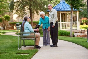 Couple pausing on outdoor walking path to talk to friends and pet a small dog