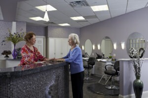 Woman standing at hair salon counter talking to other woman