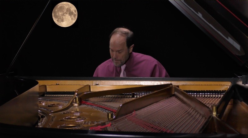 Frederick Moyer sitting and playing the piano with a moon in the background