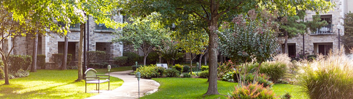 Outdoor area of Covenant Senior Living Inverness with a bench and lush plants