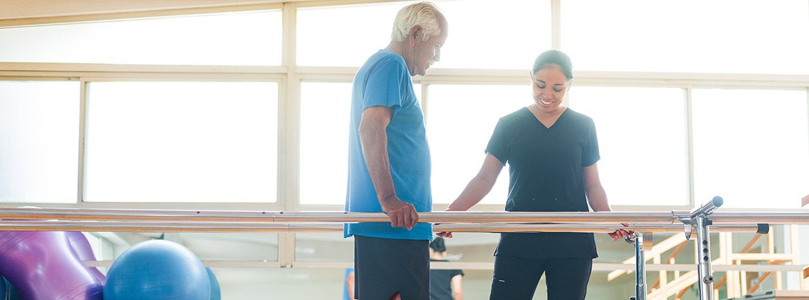 Senior man giving small steps in parallel bars