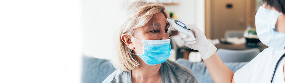 Female doctor measured temperature of the senior patient